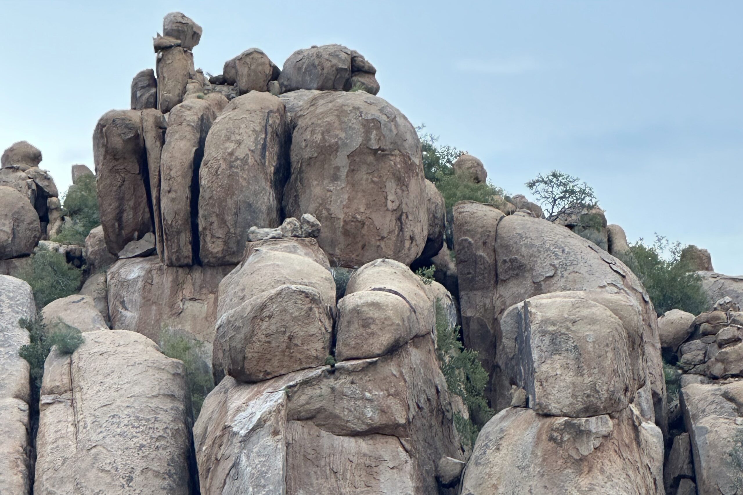Felsformation in Namibia, die an eine Gruppe von Figuren erinnert, vor weitem Himmel