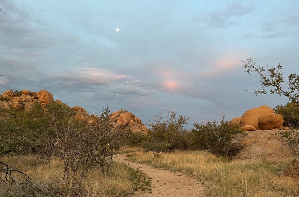 Landschaft in Namibia mit weitem Himmel, Felsen und einem sandigen Weg als Bild für Weite, Stille und innere Prozesse.