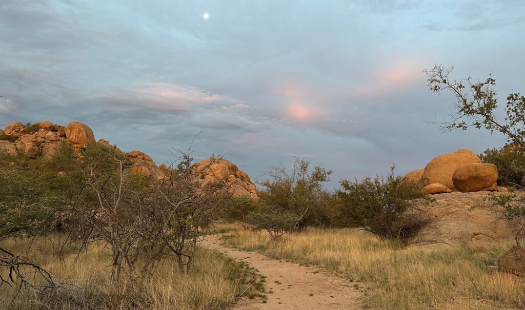 Landschaft in Namibia mit weitem Himmel, Felsen und einem sandigen Weg als Bild für Weite, Stille und innere Prozesse.